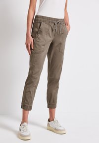 Pantalons de jogging légers couleur olive avec une taille élastique et un cordon de serrage, dotés de deux poches latérales et de poignets élastiques aux chevilles.