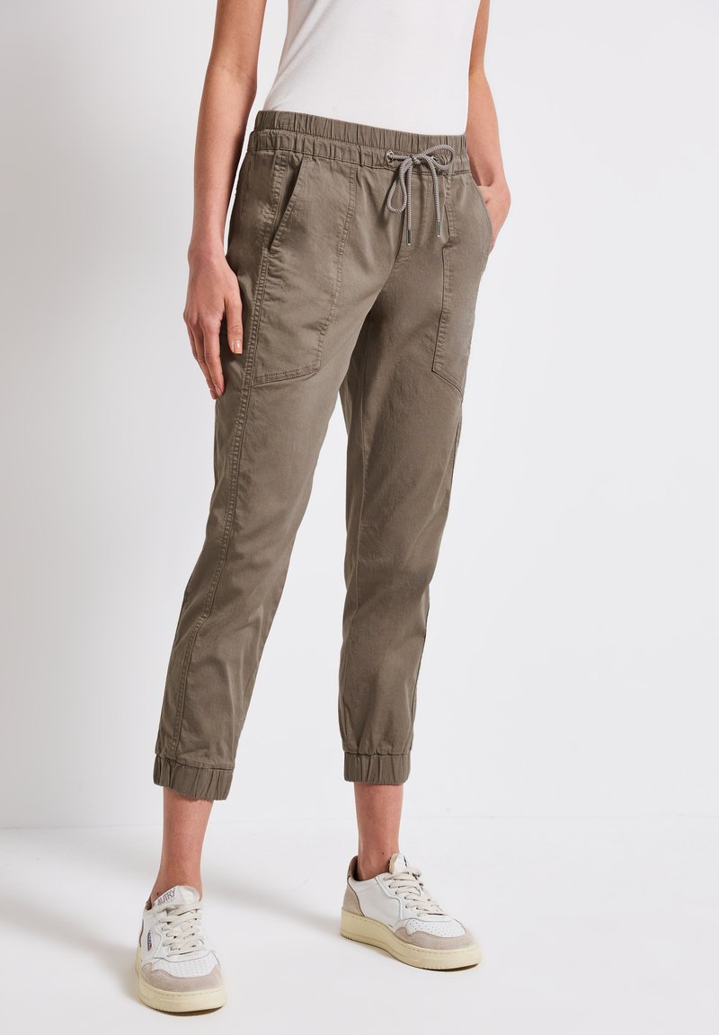 Pantalons de jogging légers couleur olive avec une taille élastique et un cordon de serrage, dotés de deux poches latérales et de poignets élastiques aux chevilles.