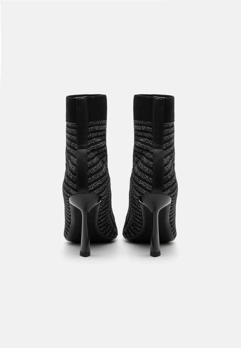 Des bottines noires en tissu présentent un design en maille texturée avec des rayures horizontales et un talon aiguille noir brillant.