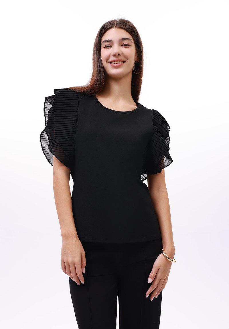 Černý top s krátkými, volánkovými průhlednými rukávy, kulatým výstřihem a klasickým střihem. Hladká textura a jednoduchý design.