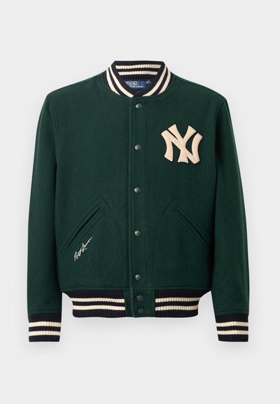 Jachetă varsity de culoare verde închis, cu manșete și guler cu dungi, unclăci cu capse, logo-ul New York Yankees pe piept și semnătura Ralph Lauren lângă buzunar.