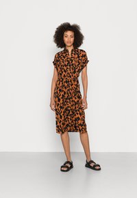 Rochie cu butoni, de culoare portocalie, cu imprimeu animalier negru, cu mâneci scurte, talie marcata cu un cureaua, până la genunchi, asociată cu sandale negre.