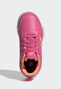 Scarpa sportiva rosa con parte superiore in pelle texture, lacci in tessuto, accenti arancioni e suola bianca. Presenta il logo sulla linguetta e sul lato.
