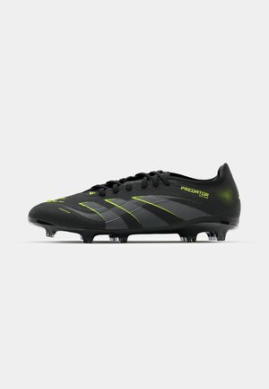 Zwarte voetbalschoenen met groene accenten, voorzien van een geprofileerde bovenkant, vetersluiting en zes transparante studs voor grip op de zool.
