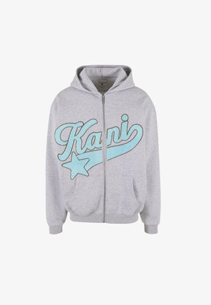 Hallide tumedast kangast valmistatud hall kapuutsiga jakk. Omab sinist tikandit "Kani" ja tähtkuju. Seal on ees taskud ja kapuuts.