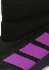 Zwarte textiele laars met paarse accenten. Bevat een gewatteerde textuur en een gevoerd kraagje voor comfort en isolatie. Duurzame zool.