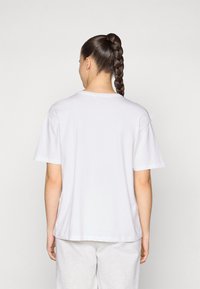 Tricou alb din bumbac, cu mâneci scurte și o croială lejeră. Prezintă un guler rotund și are o textură netedă, mata.
