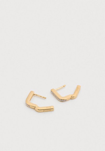 Σκουλαρίκια σε χρυσό τόνο με γεωμετρικό σχέδιο και καμπυλωτό σχήμα, διακοσμημένα με μικρούς διαφανείς λίθους κατά μήκος μιας πλευράς.