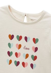 Haut en coton beige clair présentant une grille de cœurs multicolores dans différentes nuances, avec le mot « love » en cursive au centre.