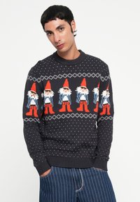 Dunkelblauer Strickpullover mit wiederholten Zwergenmustern in Rot, Weiß und Blau, mit punktierter Textur sowie gerippten Bündchen und Saum.