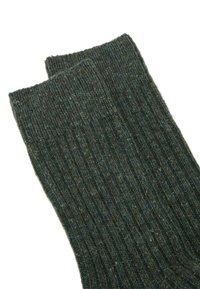Calcetines verdes acanalados hechos de una mezcla de lana texturada. Presentan un puño en la parte superior y un color oscuro y apagado con sutiles variaciones.