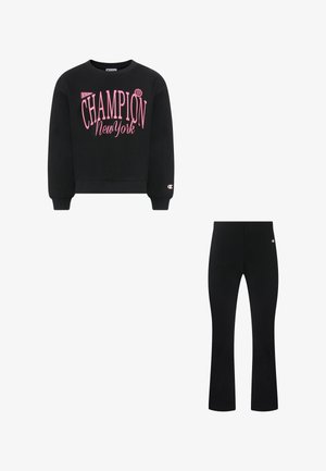 Zwarte sweatshirt met roze "Champion New York" tekst en bijpassende zwarte broek, beide met klein Champion-logo op de mouwen en heupen.