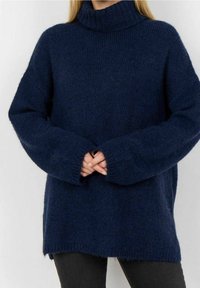 Pull à col roulé tricoté bleu marine avec une coupe décontractée, épaules tombantes et poignets côtelés. Texture douce et fentes latérales à l'ourlet.