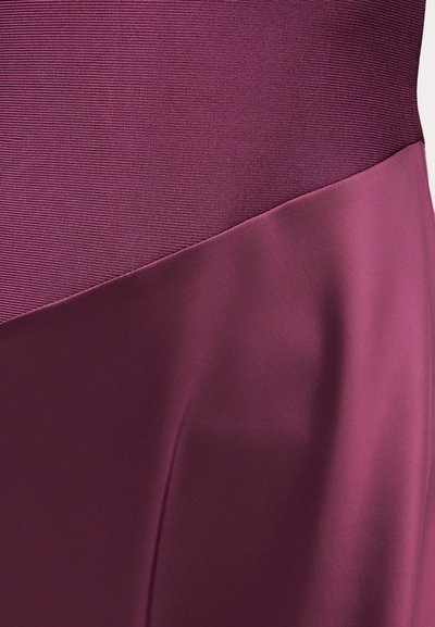 Κοντινό πλάνο μωβ ρούχου που δείχνει υφασμάτινη ριγέ υφή να συναντά λείο σατέν ύφασμα σε διαγώνια ραφή.