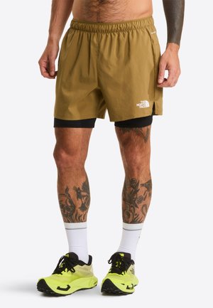 Kaki atletische shorts met een elastische tailleband en logodetail. Draag ze over zwarte compressieshorts met opvallende gele hardloopschoenen.