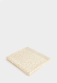 Coperta in tessuto intrecciato beige con un sottile motivo di stampa animale, caratterizzata da dettagli con frange lungo un lato. Texture liscia.