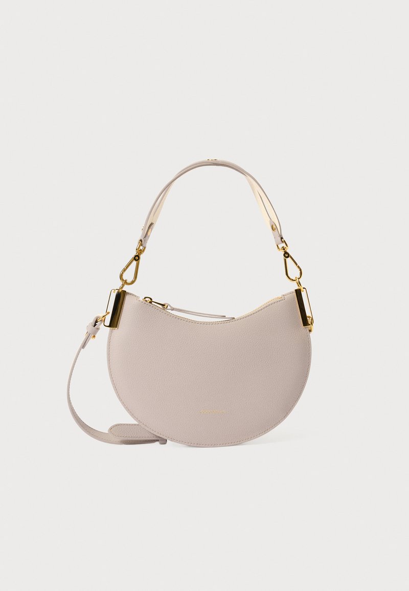 Rund, myk beige skinnhåndveske med glidelås og beslag i gulltone, med en lang justerbar rem og et minimalistisk design.