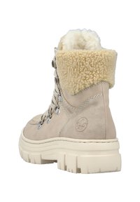 Botín de ante beige con un suave collar de piel de pelo crema, diseño con cordones, ojales de metal y una gruesa suela de goma blanca.