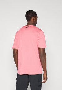 Ροζ αθλητική κοντομάνικη μπλούζα με στρογγυλή λαιμόκοψη, υφής υφάσματος και μικρό λογότυπο στην πίσω πλευρά στον αυχένα.