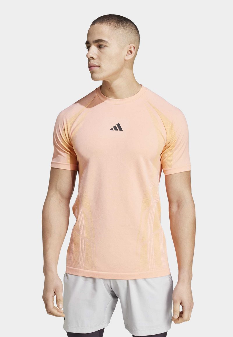 Camisa deportiva de manga corta en rosa claro, con un logo negro y acentos texturizados a lo largo de los lados para una mejor transpirabilidad.
