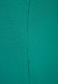 Tejido de algodón acanalado en color teal con una textura suave, que presenta una costura central. El color es uniforme sin patrones ni acentos.