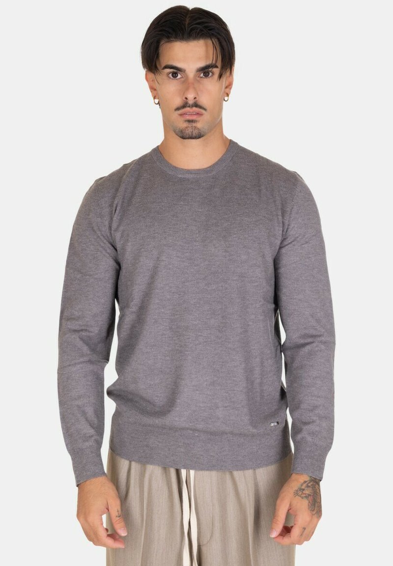 Maglione grigio a girocollo con maniche lunghe, realizzato in tessuto morbido. Presenta un orlo e polsini a costine, e un logo sottile sul lato inferiore.