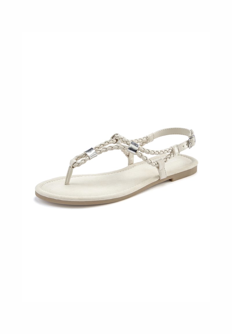 Beige flat sandal with woven strap design and silver-tone hardware accents. Features a minimal sole and adjustable ankle strap.