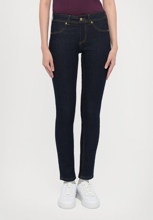 Dark blue skinny jeans made of denim, featuring a classic five-pocket design, gold stitching, and a button closure at the waist.