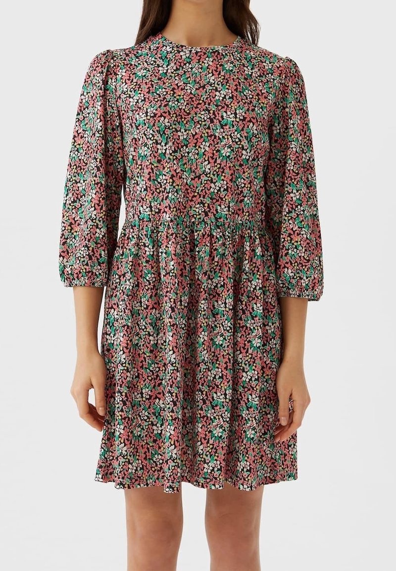 Robe imprimée fleurie avec un col rond, des manches trois-quarts et une jupe évasée. Les couleurs comprennent le rose, le vert et le blanc sur un fond noir.