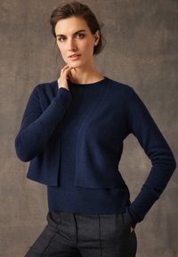 Granatowy krótkowłosy sweter wykonany z miękkiego materiału, z okrągłym dekoltem i długimi rękawami z ściągaczami na mankietach i u dołu.