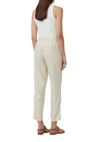 Lichtbeige linnenbroeken met een elastische tailleband, rechte snit en twee achterzakken. G gedragen met een aansluitend wit tanktop en sandalen.