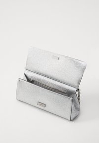 Silver metallic clutchväska med en slät, glittrig yta. Har en kedjesnor och ett zippert fack inuti. Kompakt rektangulär form.