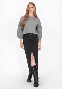 Grå striktrøje med puffede ærmer, parret med en lang sort denimnederdel med en slids foran og sorte knæhøje støvler.