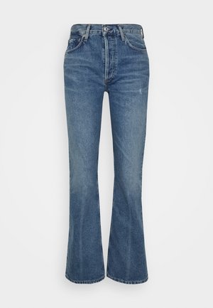 Dżinsy z wysokim stanem i rozszerzanymi nogawkami w średnim niebieskim odcieniu dżinsu z delikatnym efektownym wyblaknięciem, pięciokieszeniowym krojem i tradycyjnym metalowym zapięciem na guzik.