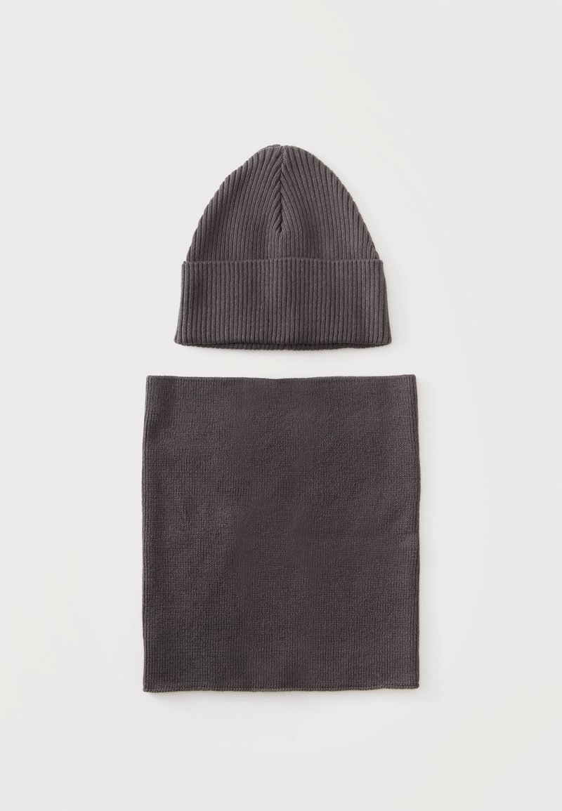 Bonnet en maille côtelée gris foncé associé à une écharpe rectangulaire en maille gris foncé assortie sur fond blanc.