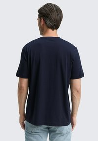Tricou din bumbac de culoare bleumarin, cu mâneci scurte și guler rotund, expus din spate. Textură netedă, croială casual.