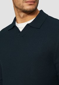 Donkerblauwe textuur polo shirt met een V-hals en korte kraag, met een ribgebreide halslijn en een gladde binnenlaag.