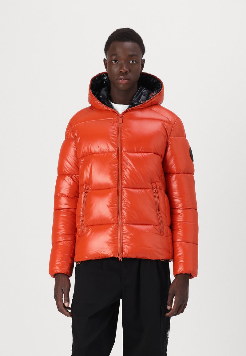 Padded orange parka jacket with a shiny texture, zippered front, adjustable hood, and two front pockets. Black lining and logo patch.