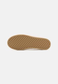Rubber sneaker sole with a woven pattern, tan color, textured surface, and rounded toe shape. Slightly raised edge around the perimeter.