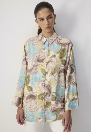 Camicia button-up floreale con una combinazione di colori pastello, grandi motivi floreali e un taglio morbido con maniche lunghe e colletto a punta.