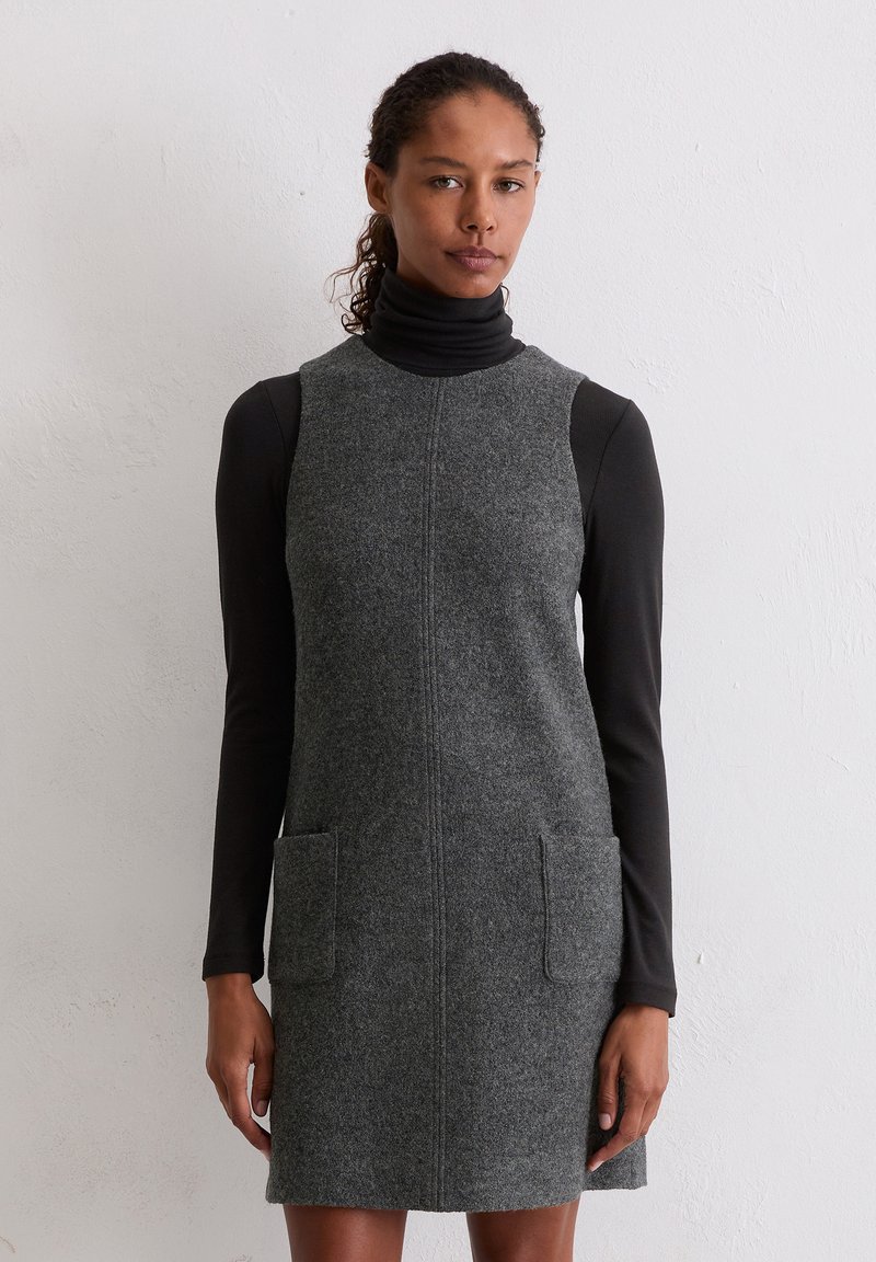 Grijs wollen jurk met een mouwloos ontwerp, voorzien van een hoge hals en twee voorzakken. Gladde textuur en rechte silhouette.