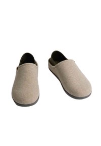 Béžové plstěné nazouvací boty s měkkou texturou, zaobleným tvarem a černou gumovou podrážkou. Minimalistický design bez viditelného kování nebo akcentů.