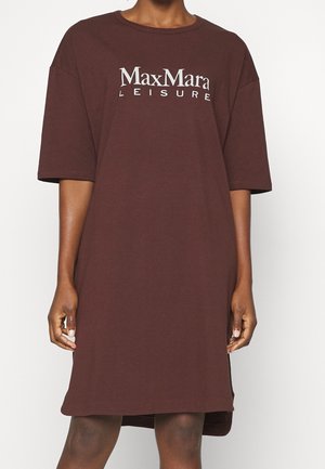 Person iført en løs, knælængde brun kjole med "MaxMara LEISURE" trykt i hvidt hen over brystet.
