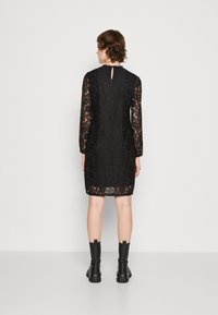 Black lace dress with long sleeves, floral pattern, and a keyhole back detail. Paired with black ankle boots.