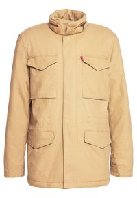 Kaki jacka med hög krage, två bröstfickor och sidfickor. Tillverkad i ett kraftigt tyg med dragkedjestängning och subtila sömnadsdetaljer.