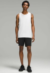 Hvid sleeveless tank top parret med sorte shorts. Stoffet er glat med en afslappet pasform. Sorte atletiske sko fuldender outfittet.