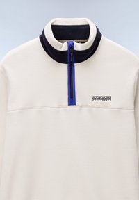 Fleece pullover in cream with a navy collar. Features a quarter-zip front with blue accents and a small black logo on the chest. Soft texture.