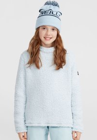 Pull en polaire bleu clair avec une surface douce et texturée et un col montant. Associé à un bonnet bleu assorti avec un logo sombre et un pompon.