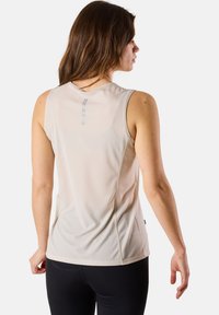 Light beige sleeveless athletic top with a textured, breathable fabric. Features a reflective strip on the back and flat seams for comfort.