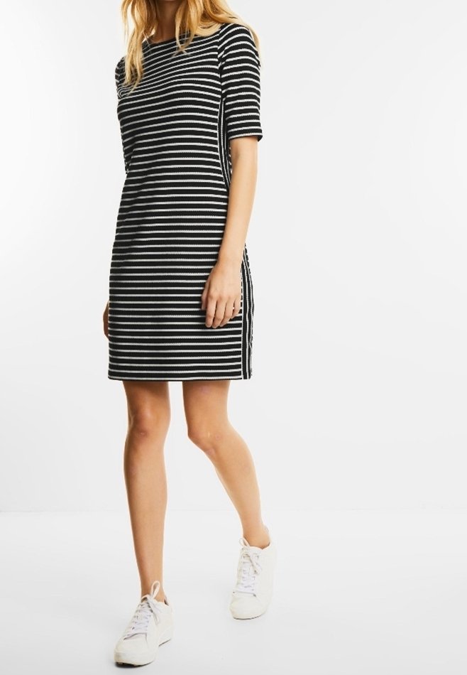 Randig klänning i svart och vitt med korta ärmar, rak skärning och sidofickor. Matchad med vita sneakers för en avslappnad look.
